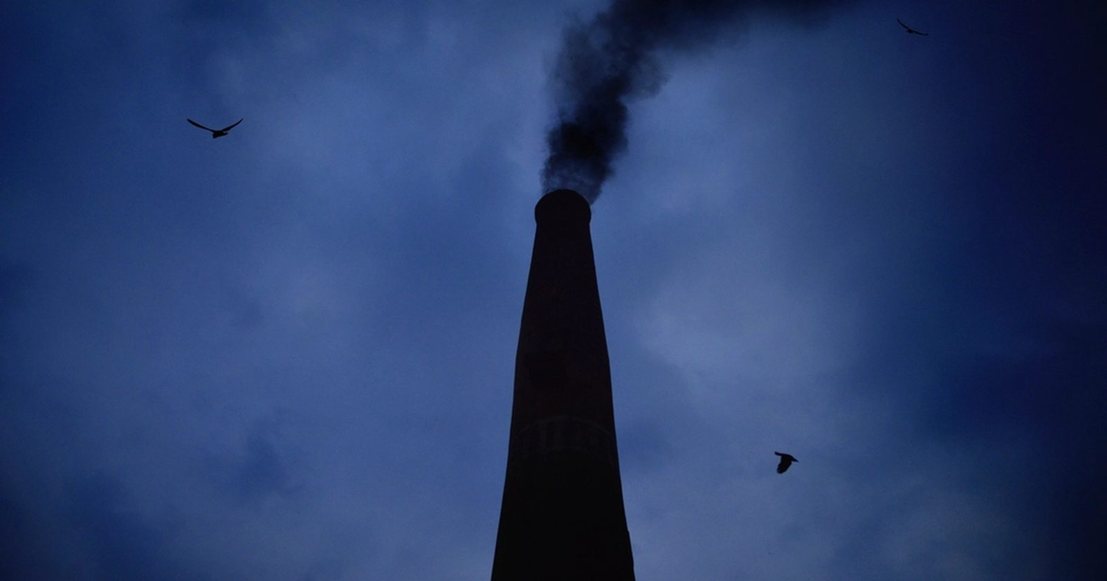 Komin fabryczny emitujący dym — źródło zanieczyszczeń wymagające kontroli.